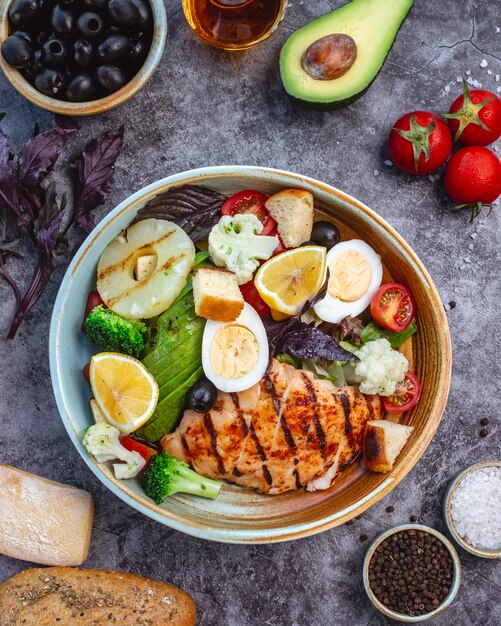 Vista superior de ensalada de dieta saludable con pollo a la parrilla, brócoli, coliflor, tomate, lechuga, aguacate y lechuga