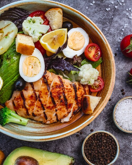 Vista superior de ensalada de dieta saludable con pollo a la parrilla, brócoli, coliflor, tomate, lechuga, aguacate y lechuga