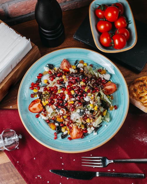 Vista superior de ensalada fresca con repollo, tomate, queso blanco y semillas de granada en un plato