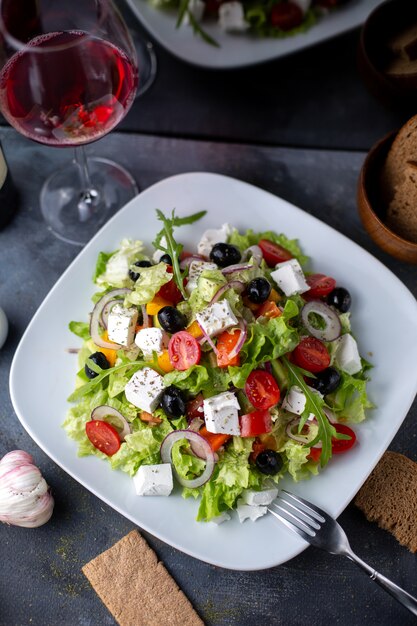 Una vista superior ensalada grecia aceitunas en rodajas vino tinto dentro de plato blanco