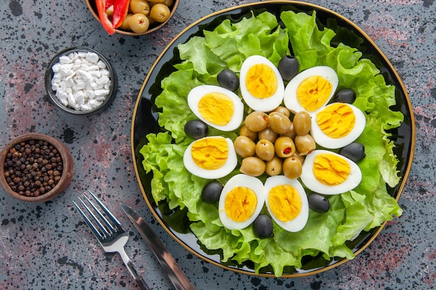 Vista superior de la ensalada de huevo se compone de ensalada verde y aceitunas sobre un fondo claro