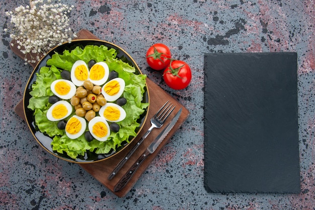 Vista superior de ensalada de huevo ensalada verde y aceitunas con tomates rojos sobre fondo claro