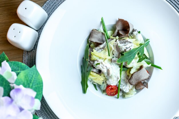 Vista superior ensalada de lengua de vaca con mayonesa lechuga y rúcula en un plato