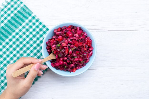 Vista superior de la ensalada de remolacha en rodajas con verduras dentro de la placa azul en la mesa de luz, ensalada de salud de comida vegetal con vitamina