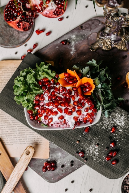 Vista superior de ensalada de remolacha con salsa mayonesa y granada en una tabla de madera