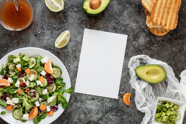 Vista superior ensalada saludable con hoja de papel en blanco