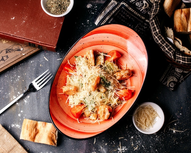 Vista superior ensalada con trozos de pollo y verduras frescas en el oscuro escritorio