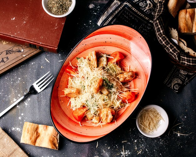 Vista superior ensalada con trozos de pollo y verduras frescas en el oscuro escritorio