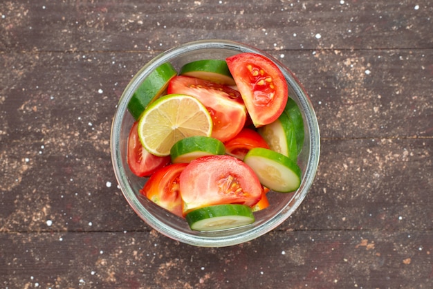 Vista superior ensalada de vegetales con pepinos en rodajas tomates y limón en ensalada de comida de limón jugo de vegetales marrón