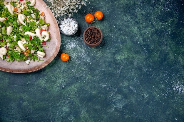 Vista superior ensalada de verduras dentro de un elegante plato con cubiertos sobre fondo azul oscuro cocina almuerzo salud dieta color cocina cena en forma restaurante comida espacio libre