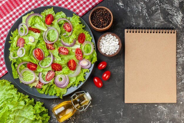 Vista superior de ensalada de verduras frescas con cebollas, ensalada verde y tomates sobre fondo gris, color de salud, ensalada madura, comida, dieta, comida, foto