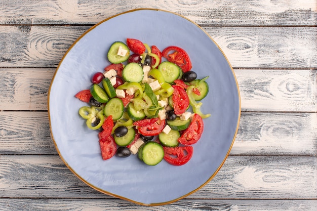 Vista superior Ensalada de verduras frescas con pepinos en rodajas, tomates, aceituna, placa interior en superficie gris, comida vegetal, ensalada, color de comida