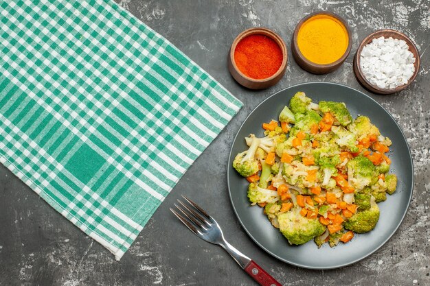 Vista superior de ensalada de verduras frescas y saludables en una toalla despojada verde en la mesa gris