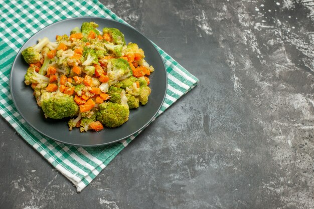 Vista superior de ensalada de verduras frescas y saludables en una toalla despojada verde en la mesa gris