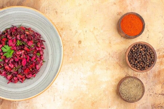 Vista superior de ensalada de verduras con hojas de perejil con pimienta negra molida, pimienta negra y cúrcuma en una mesa de madera con espacio para texto en el medio