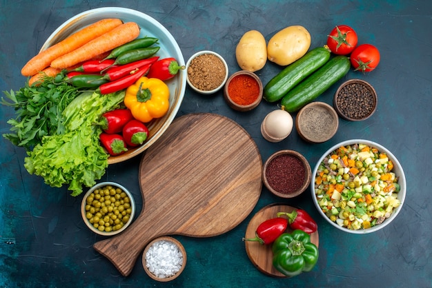 Vista superior de ensalada de verduras en rodajas aderezado con rodajas de pollo dentro de la placa con verduras frescas en el escritorio azul, almuerzo, ensalada, comida vegetal