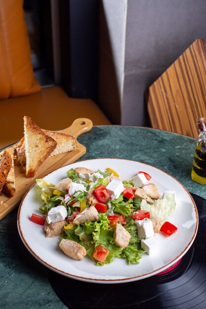 Una vista superior de ensalada de verduras con rodajas de pollo y pan en la mesa verde comida comida verduras