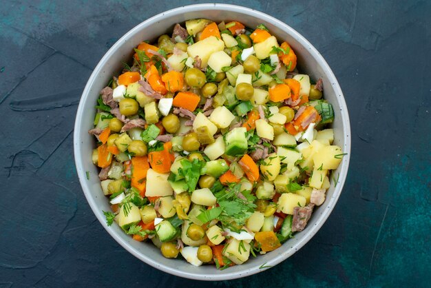 Vista superior de ensalada de verduras en rodajas salpicado con rodajas de pollo dentro de la placa en el escritorio de color azul oscuro ensalada comida de verduras merienda almuerzo