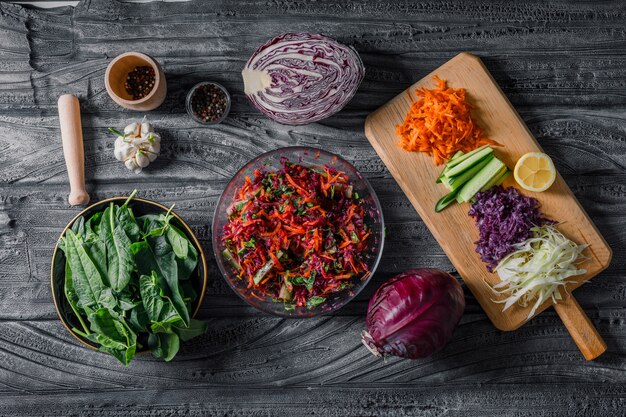 Vista superior ensalada de verduras con verduras en rodajas, verduras y especias sobre fondo de madera oscura. horizontal
