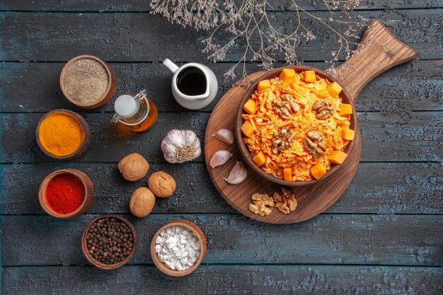 Vista superior ensalada de zanahoria fresca con nueces y condimentos en la salud de color de ensalada de dieta de nueces de escritorio azul oscuro