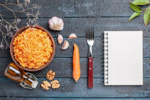 Vista superior ensalada de zanahoria rallada con ajo y nueces en el escritorio rústico azul oscuro ensalada de salud verduras dieta de color maduro