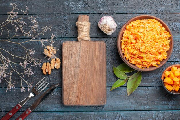 Vista superior ensalada de zanahoria rallada con ajo y nueces en el escritorio rústico oscuro ensalada de dieta saludable color naranja maduro