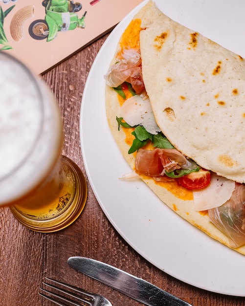 Vista superior de envoltura de carne curada con queso de tomate cherry y salsa de tomate