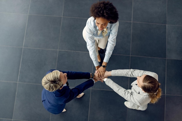 Vista superior del equipo de negocios femenino tomados de la mano en unidad