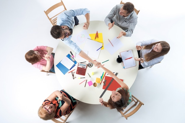 Foto gratuita vista superior del equipo de negocios smilimg, sentado en una mesa redonda sobre fondo blanco. concepto de transacción exitosa