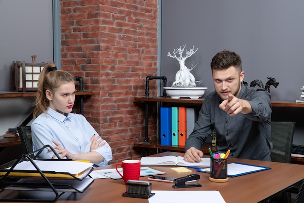 Vista superior del equipo de oficina joven trabajador sentado en la mesa discutiendo un tema importante en la oficina