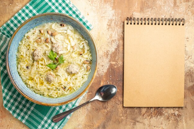 Vista superior erishte azerbaiyano en un tazón sobre una toalla de cocina una cuchara un cuaderno sobre fondo beige