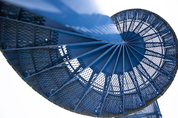 Vista superior de una escalera de caracol azul sobre un fondo blanco.