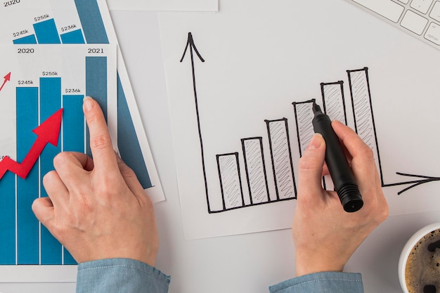 Vista superior del escritorio de oficina con tabla de crecimiento y manos