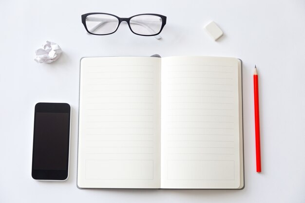 Vista superior de un escritorio de trabajo con el cuaderno abierto en blanco