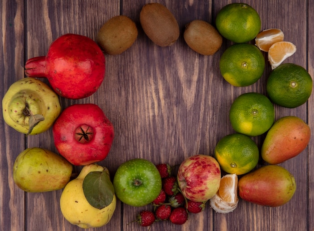 Vista superior del espacio de copia manzanas de colores con kiwi, mandarinas, peras, fresas y granadas en la pared de madera