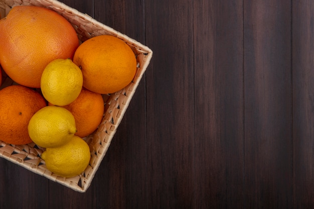 Vista superior espacio de copia naranjas en una canasta con limones y pomelos sobre un fondo de madera