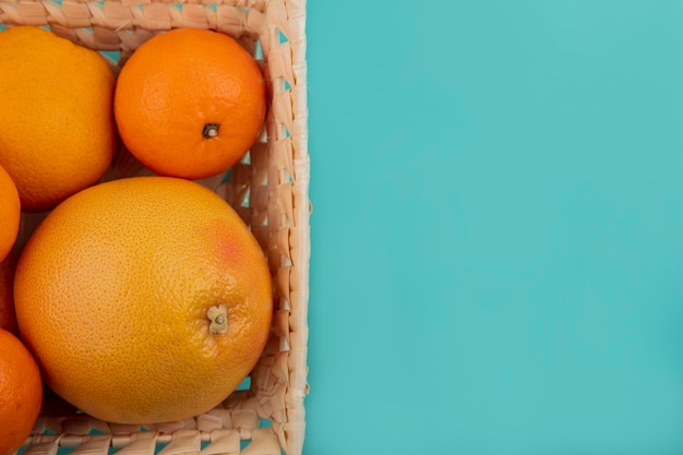 Vista superior del espacio de copia naranjas con pomelo en la canasta sobre fondo turquesa