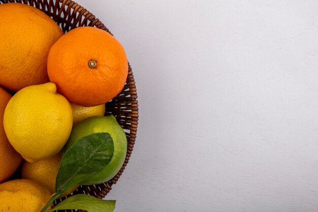 Vista superior espacio de copia pomelo con naranjas y limones en la canasta sobre fondo blanco.