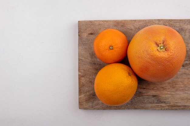 Vista superior espacio de copia pomelo con naranjas en tabla de cortar sobre fondo gris