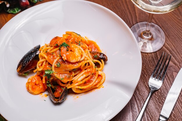 Vista superior de espagueti de mariscos con mejillones, camarones, salsa de tomate y perejil