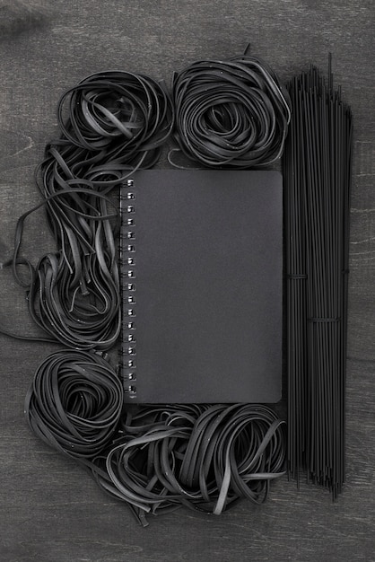 Foto gratuita vista superior de espagueti negro y tagliatelle con cuaderno