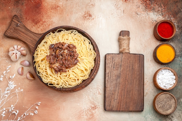 Vista superior de espaguetis cocidos con carne molida en un escritorio de madera, plato, pasta, condimento para masa