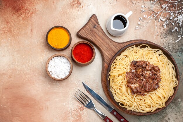 Vista superior de espaguetis cocidos con carne molida en mesa de luz plato de masa de pasta de carne