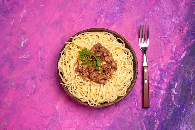 Foto gratuita vista superior de espaguetis cocidos con carne molida en pasta de masa de plato de color rosa mesa