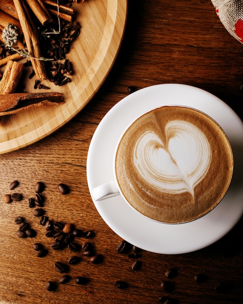 Foto gratuita vista superior de espresso caliente junto con semillas de café y canela en el piso de madera marrón