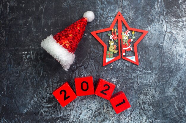 Vista superior del estado de ánimo de año nuevo con números de sombrero de santa claus y estrella con dibujos navideños en superficie oscura