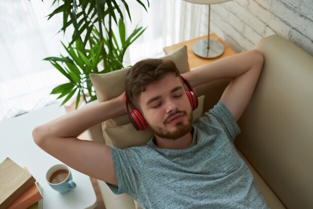 Vista superior del estudiante relajante en auriculares disfrutando de su lista de reproducción lounge