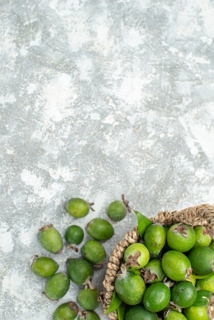 Vista superior feijoas frescas en canasta de mimbre sobre superficie gris aislada con espacio de copia