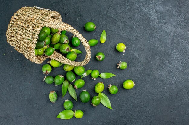 Vista superior feijoas frescas en canasta sobre superficie oscura