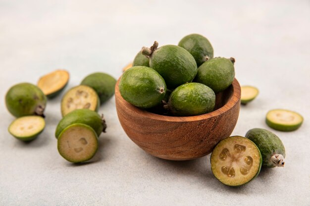 Vista superior de feijoas frescas tropicales en un cuenco de madera con feijoas aislado sobre una superficie gris